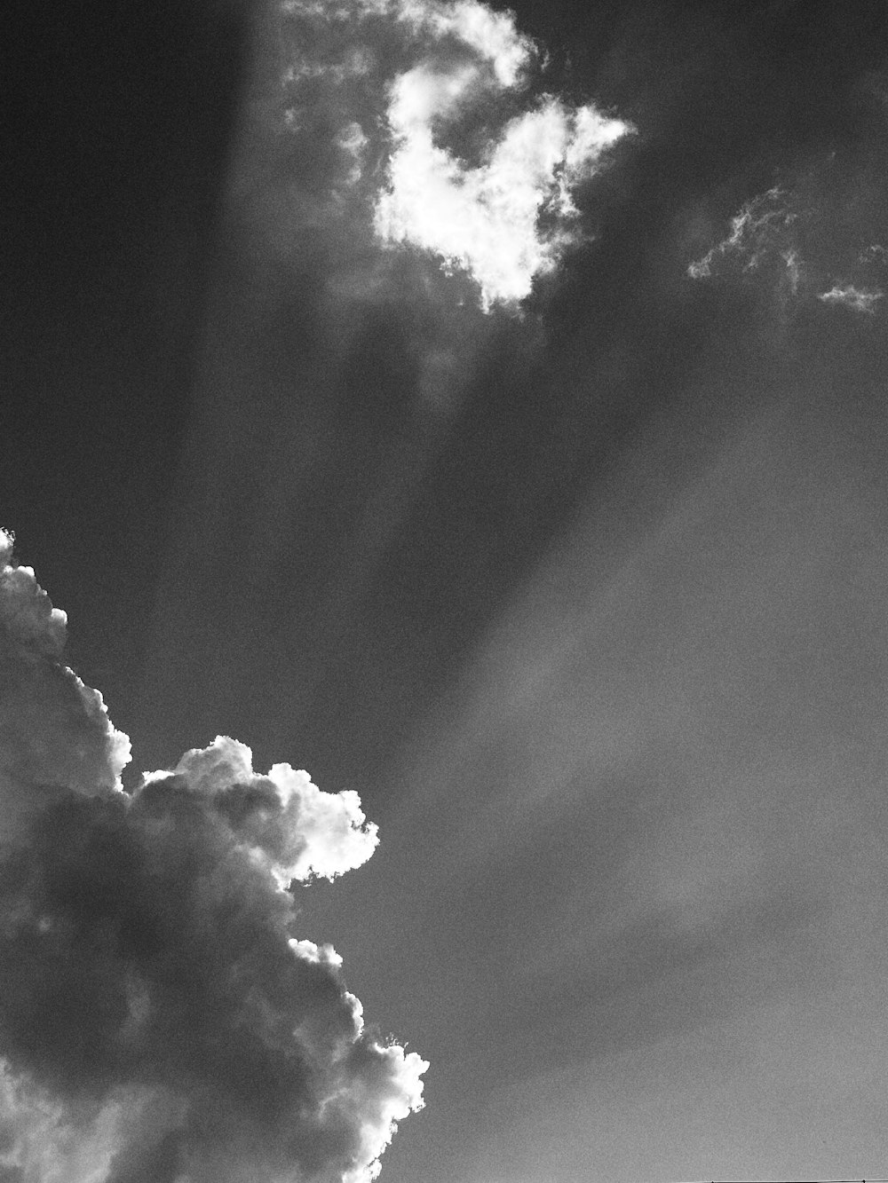 a black and white photo of the sun shining through clouds