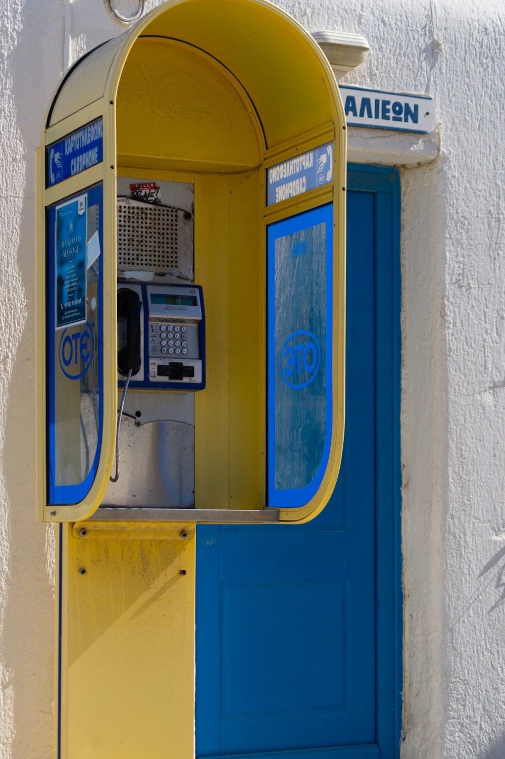 a yellow and blue phone booth next to a blue door