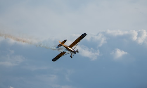 a small airplane flying through a cloudy blue sky