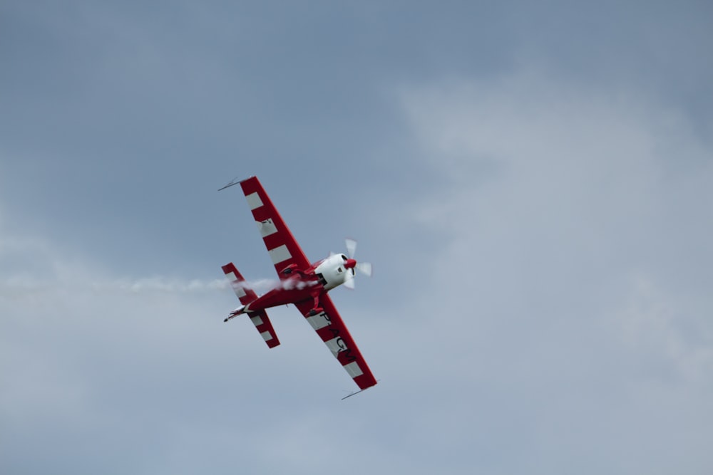 a red and white plane flying in the sky