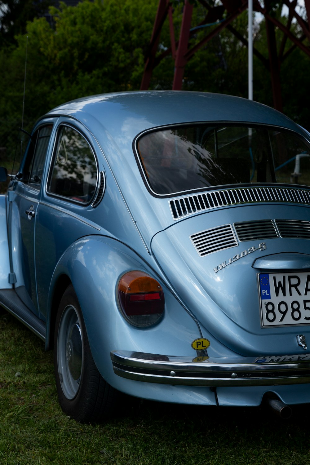 a blue vw bug is parked in the grass