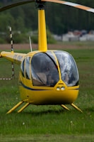 a yellow helicopter sitting on top of a lush green field