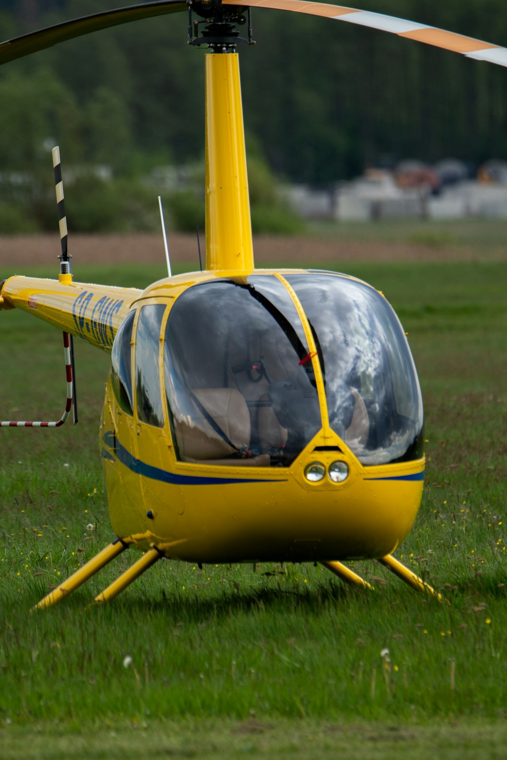 a yellow helicopter sitting on top of a lush green field