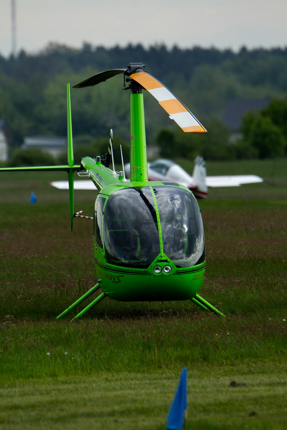 a green helicopter sitting on top of a lush green field
