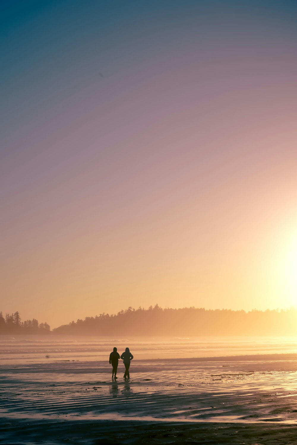 a couple of people standing on top of a beach