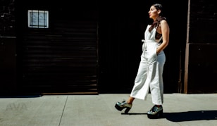 A woman in a white jumpsuit walking down a sidewalk