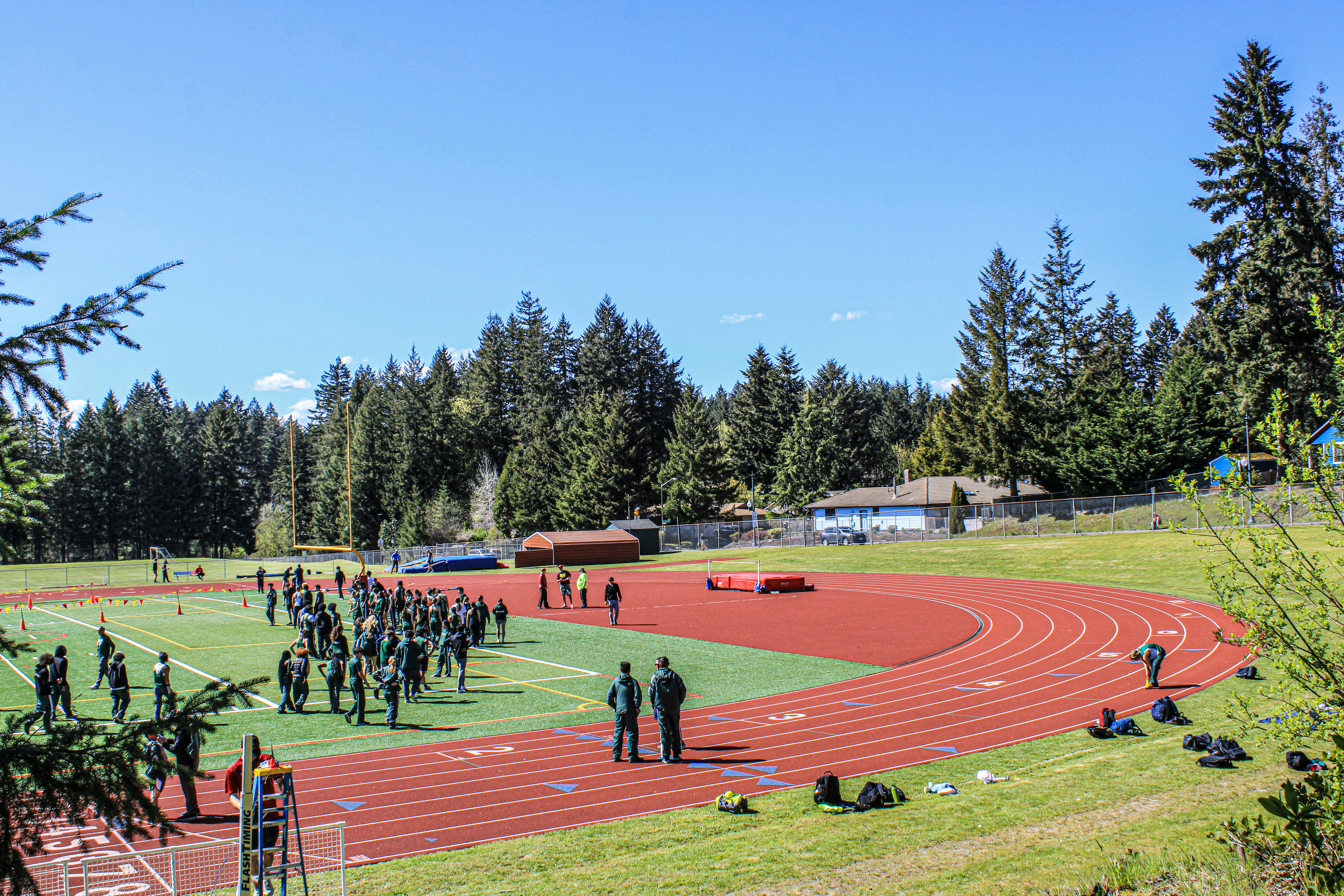 Students running track in bright outdoor sports day, green grass field, sunny Cape Town weather