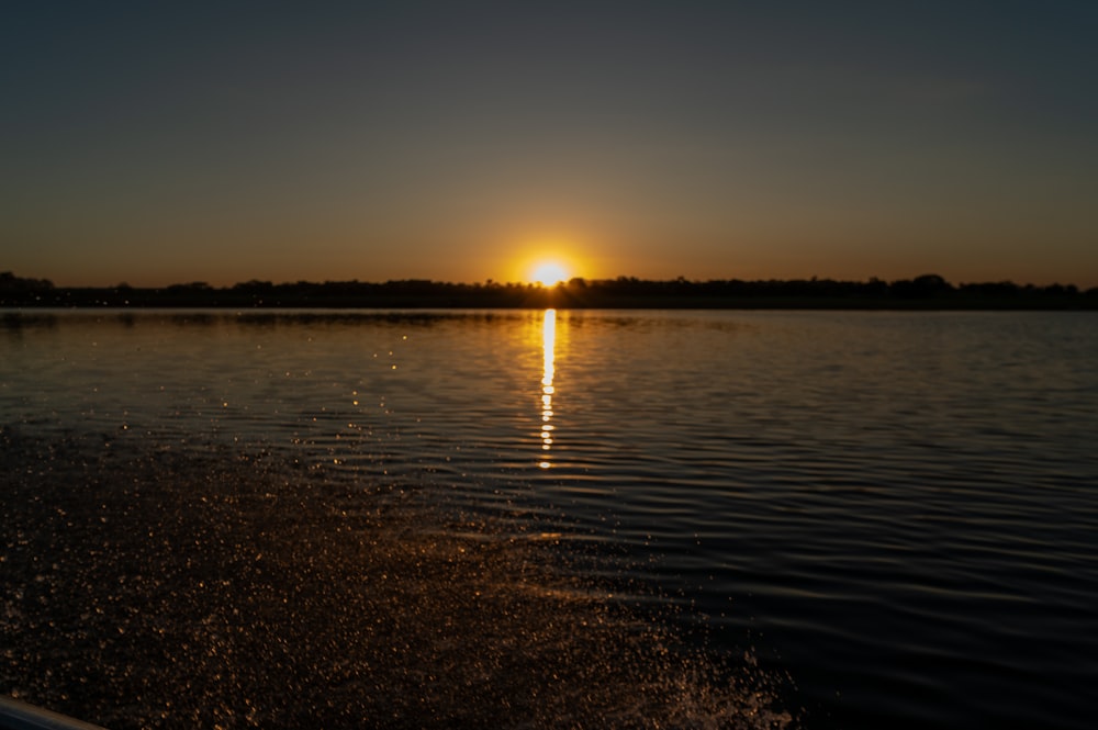 the sun is setting over the water on a boat