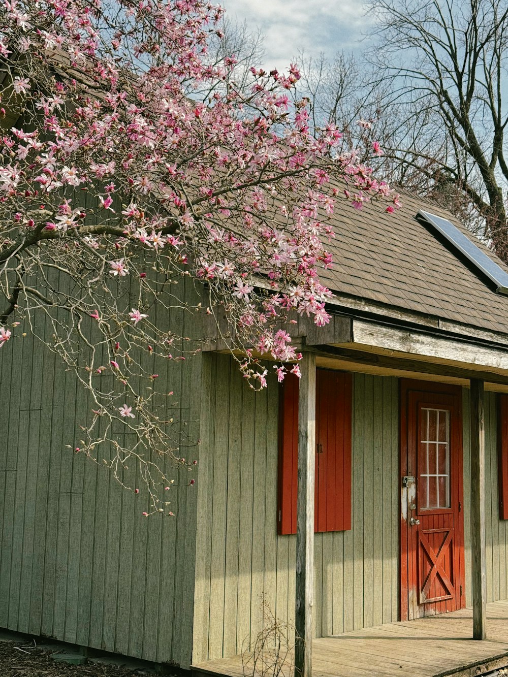 a small green building with red shutters and a red door