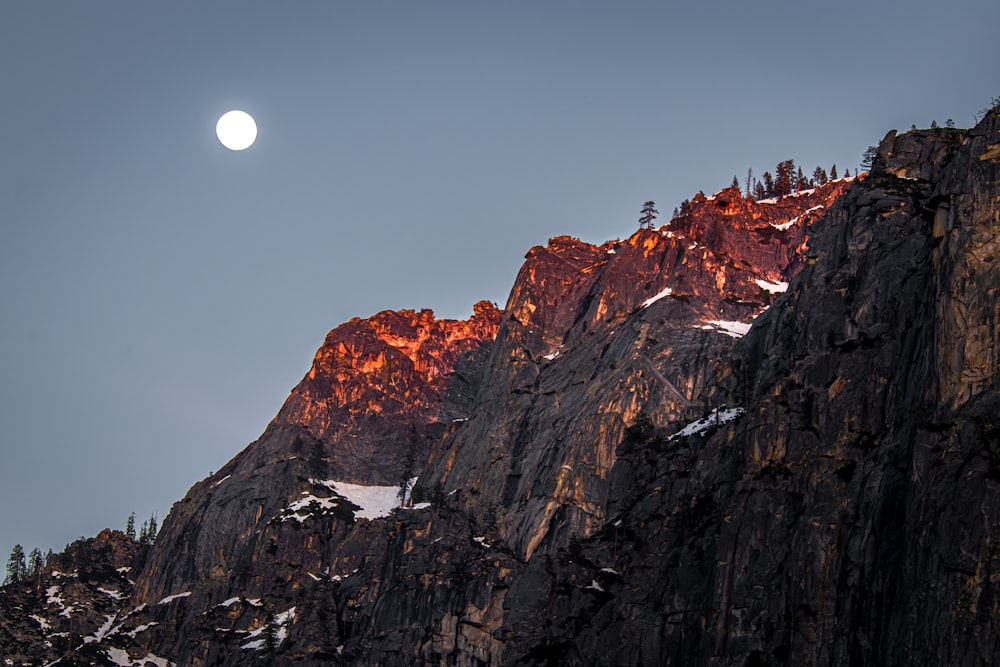 a full moon rising over a mountain range