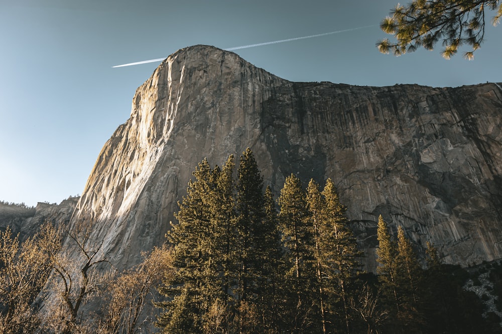 a view of a mountain with a plane flying in the sky