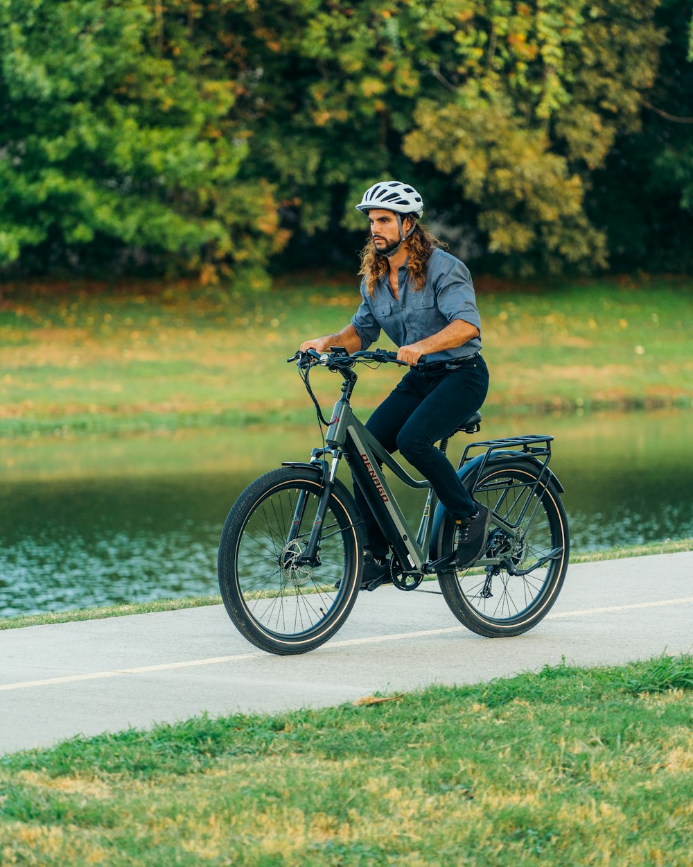 a man riding a bike down a sidewalk next to a lake