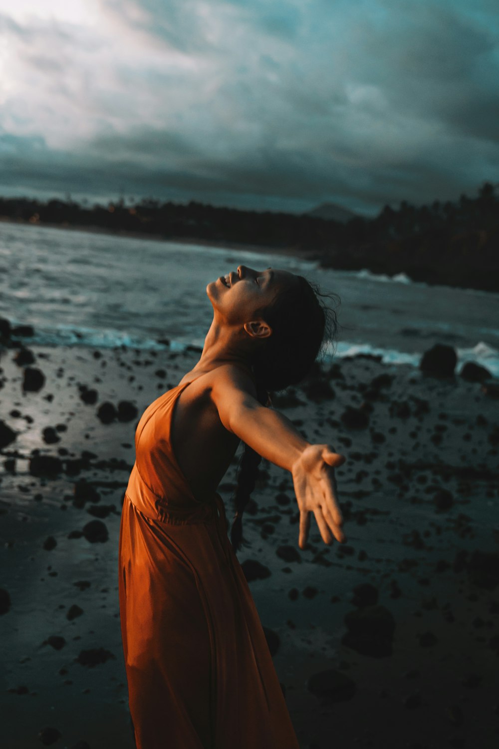 a woman in an orange dress standing on a beach