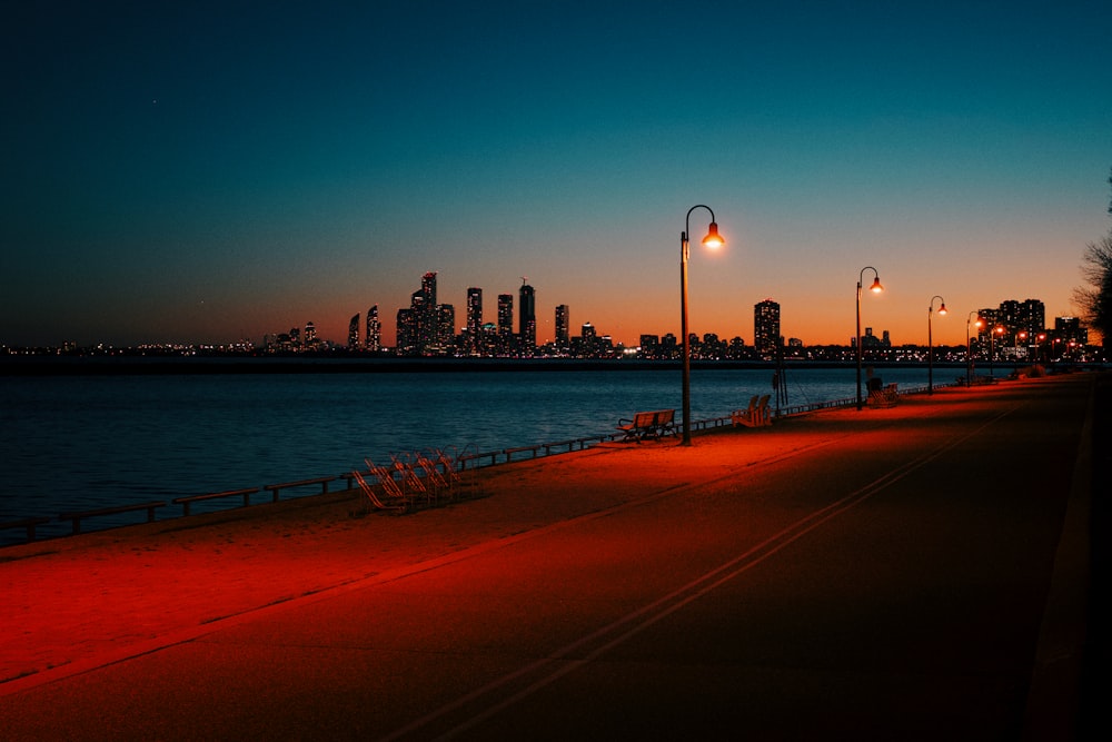 a red light shines on a street next to a body of water