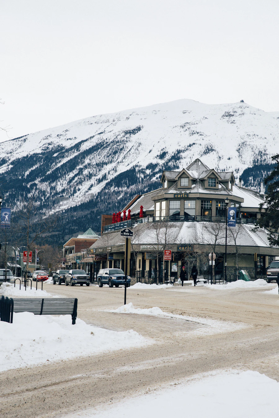 Jasper townsite with buildings and vehicles on the main street, with a snow-covered mountain rising directly behind the town