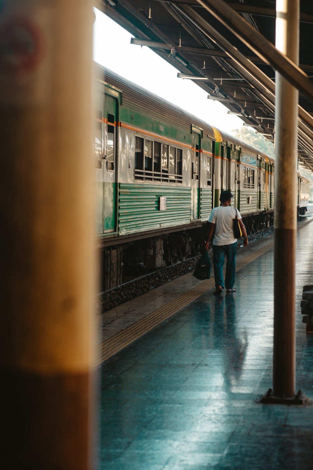 a man walking down a train platform next to a train