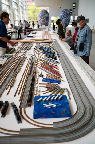 a group of people standing around a model train set