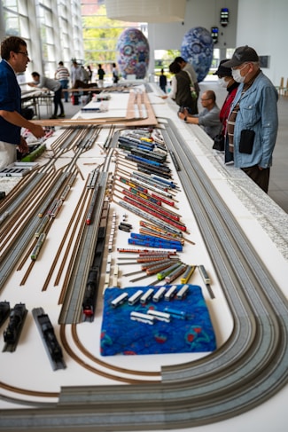 a group of people standing around a model train set