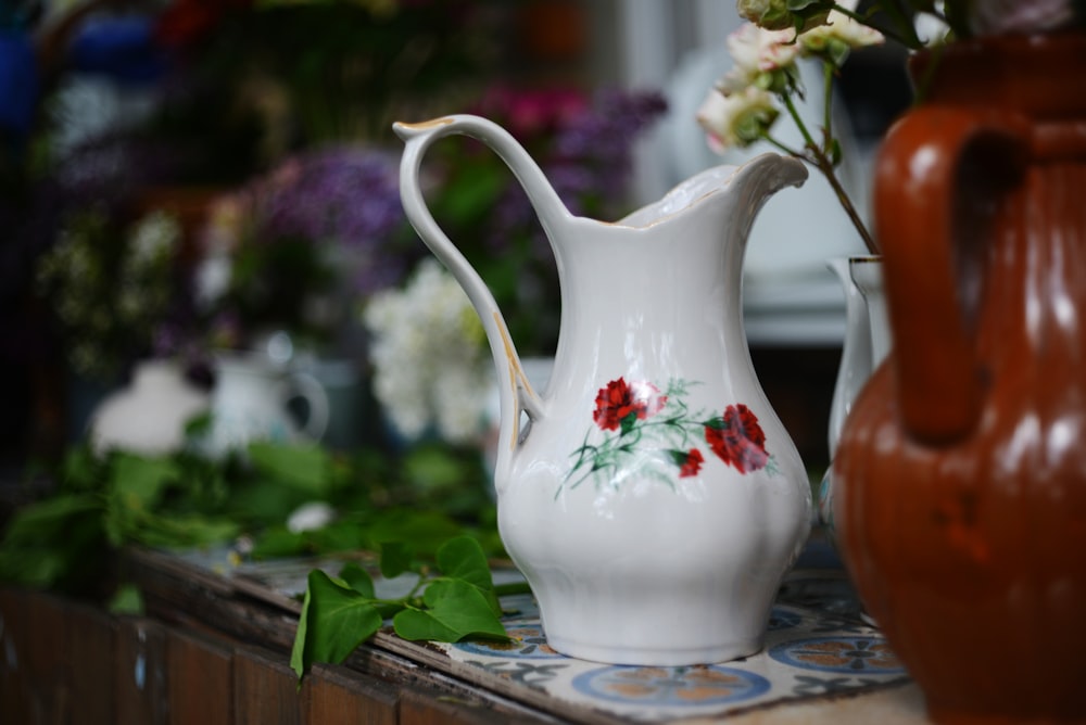 a white vase with red flowers on a table