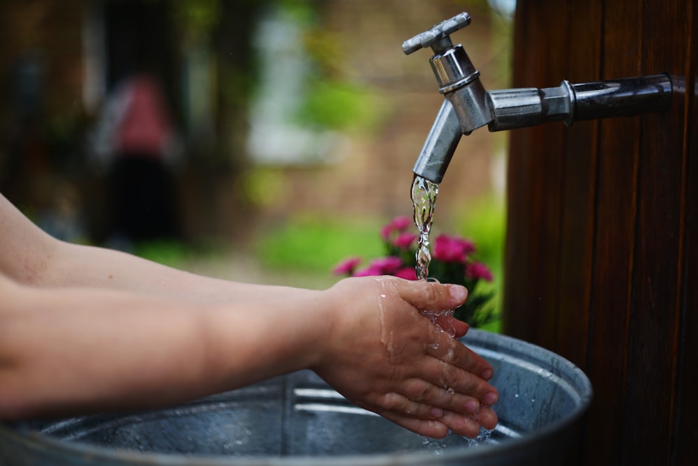 a person washing their hands under a faucet