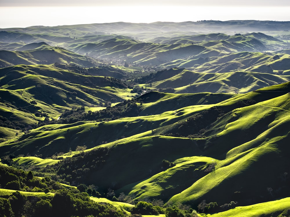 a view of a valley with green hills in the background