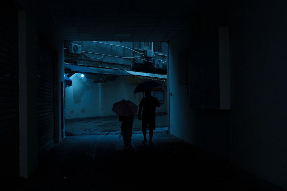 a couple of people holding umbrellas in a dark room