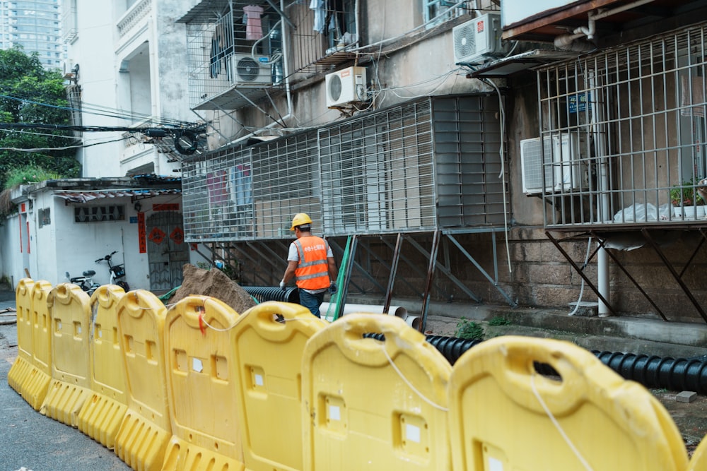 a construction worker standing next to a row of yellow barriers