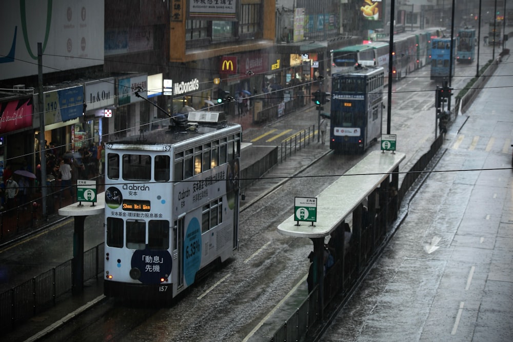 a double decker bus driving down a rain soaked street