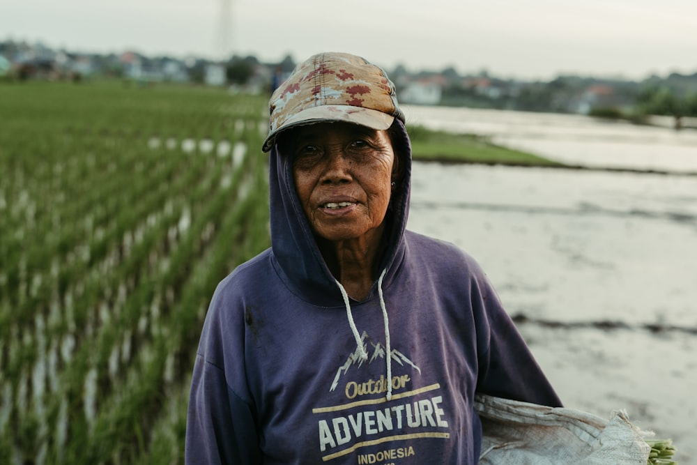 an old woman standing in front of a field