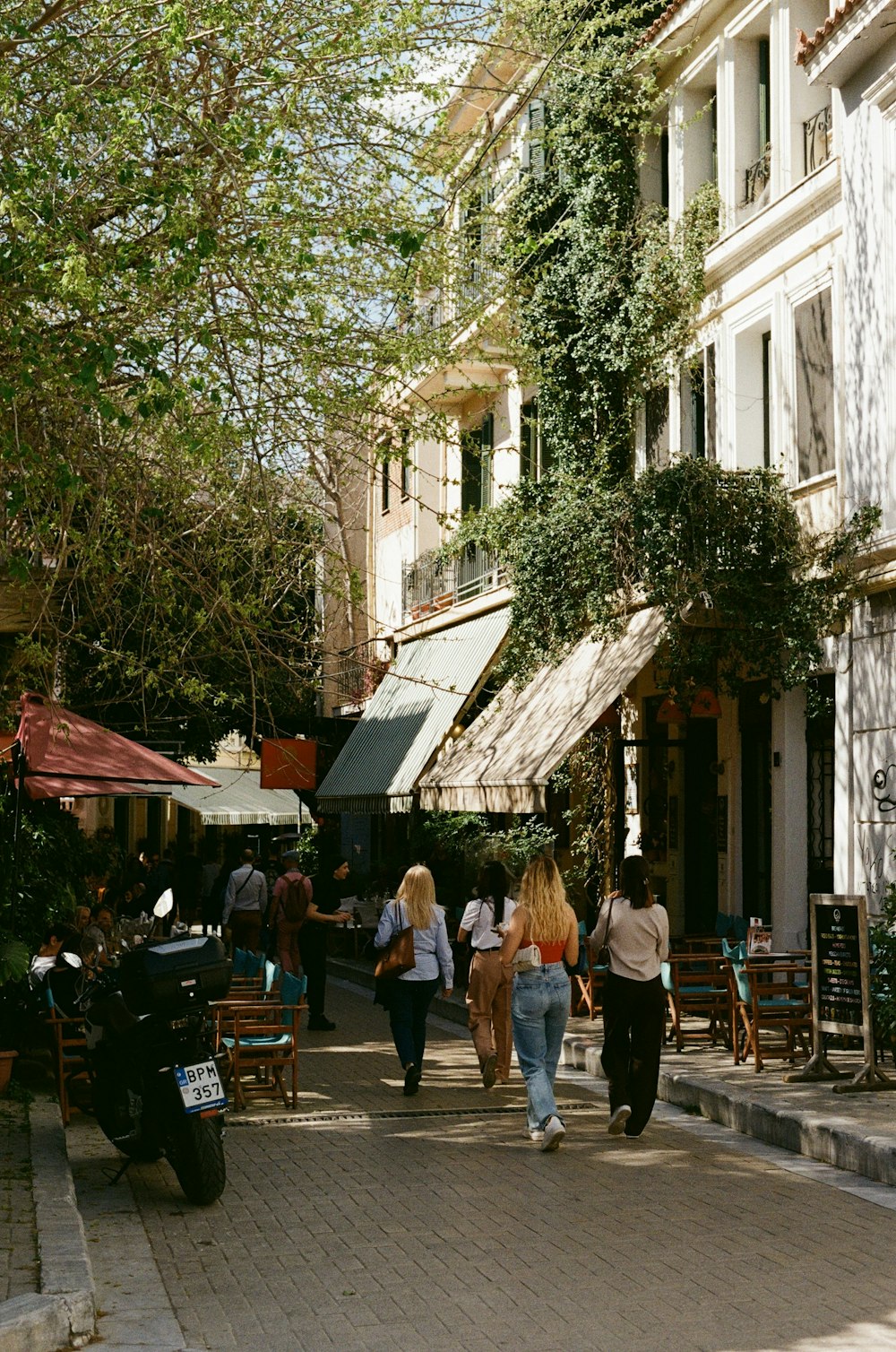 a group of people walking down a street next to tall buildings