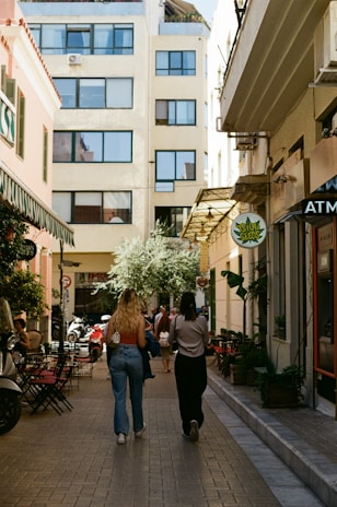 a couple of women walking down a street next to tall buildings