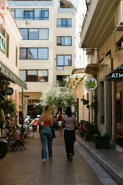 a couple of women walking down a street next to tall buildings