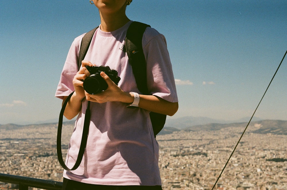 Un homme debout au sommet d’un grand immeuble tenant un appareil photo