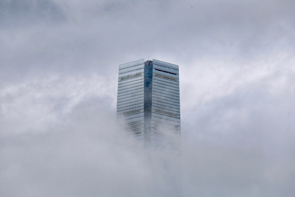a tall building in the middle of a cloud filled sky