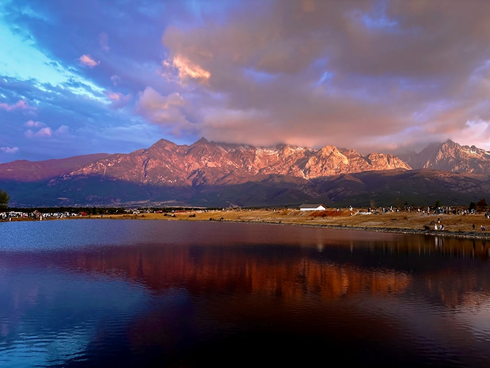 a lake surrounded by mountains under a cloudy sky