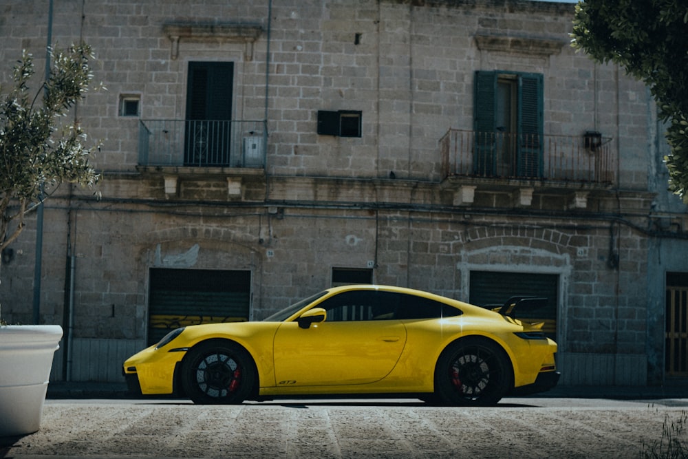 Un coche deportivo amarillo aparcado frente a un edificio