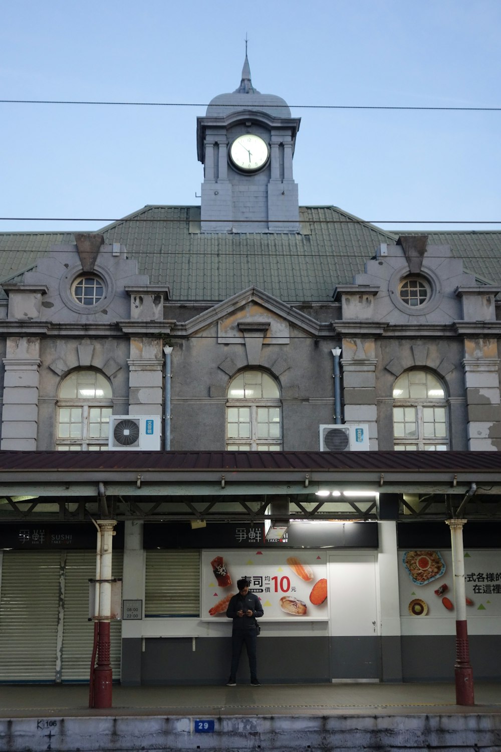 a man standing in front of a building with a clock tower