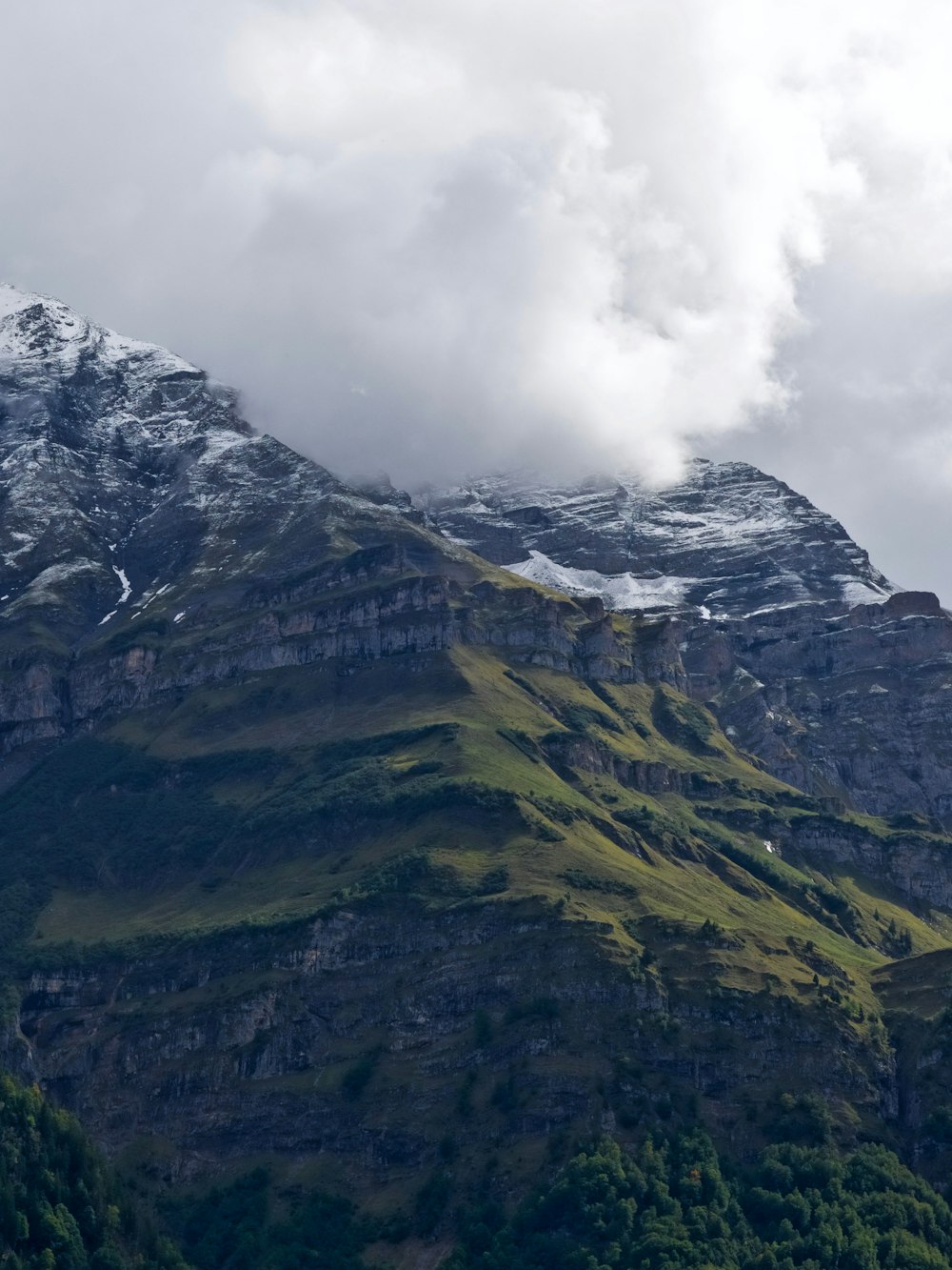 a very tall mountain covered in snow under a cloudy sky