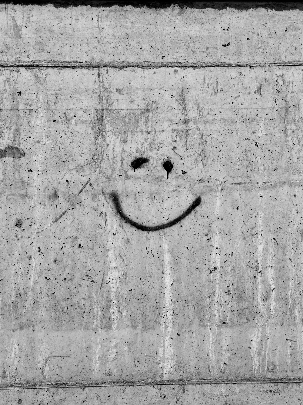 a smiley face drawn on a concrete wall