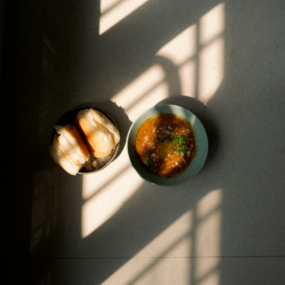 a bowl of soup next to a bowl of bread