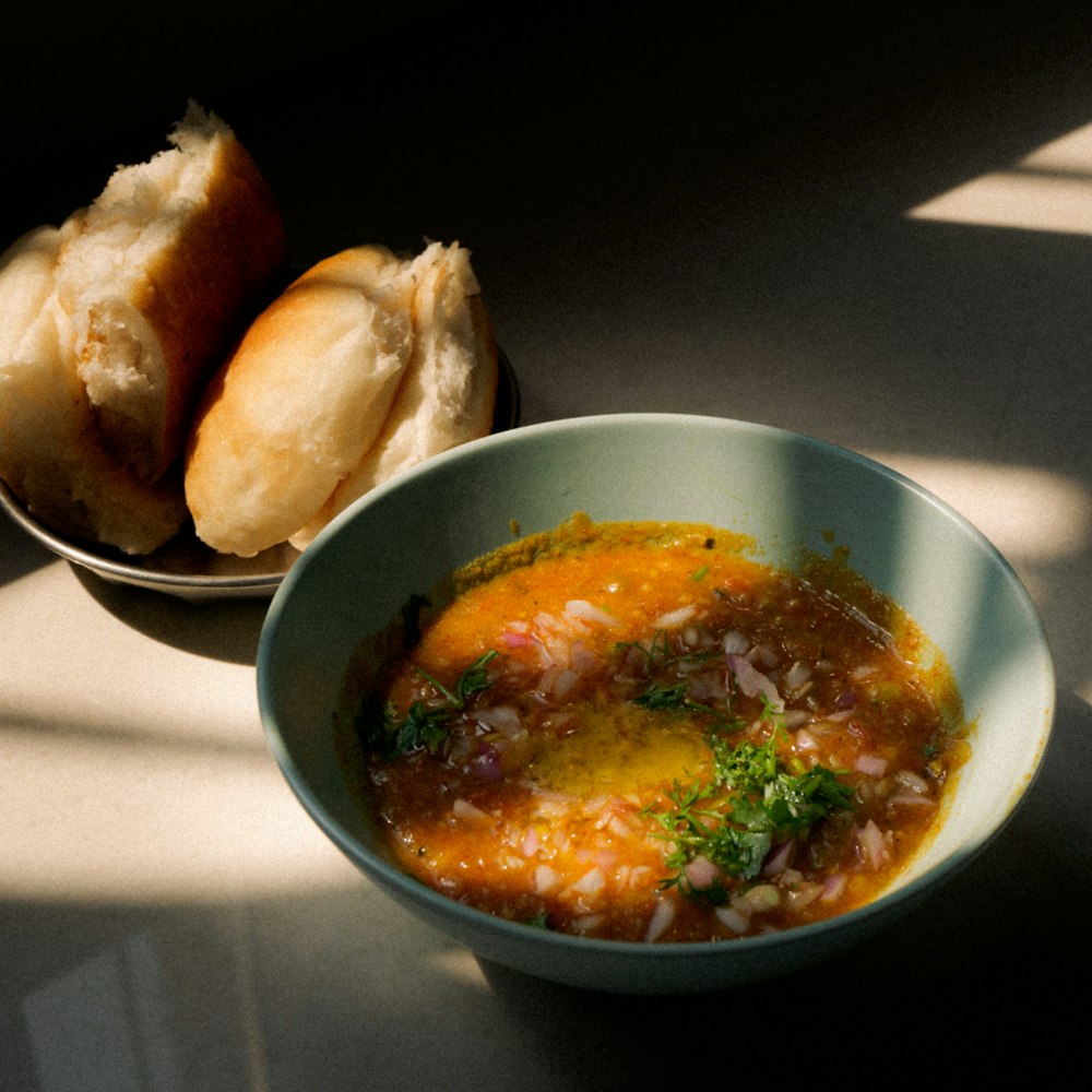 a bowl of soup next to a bowl of bread