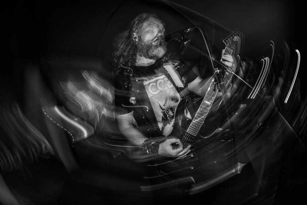 a black and white photo of a man playing a guitar