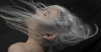 a woman with grey hair blowing in the wind