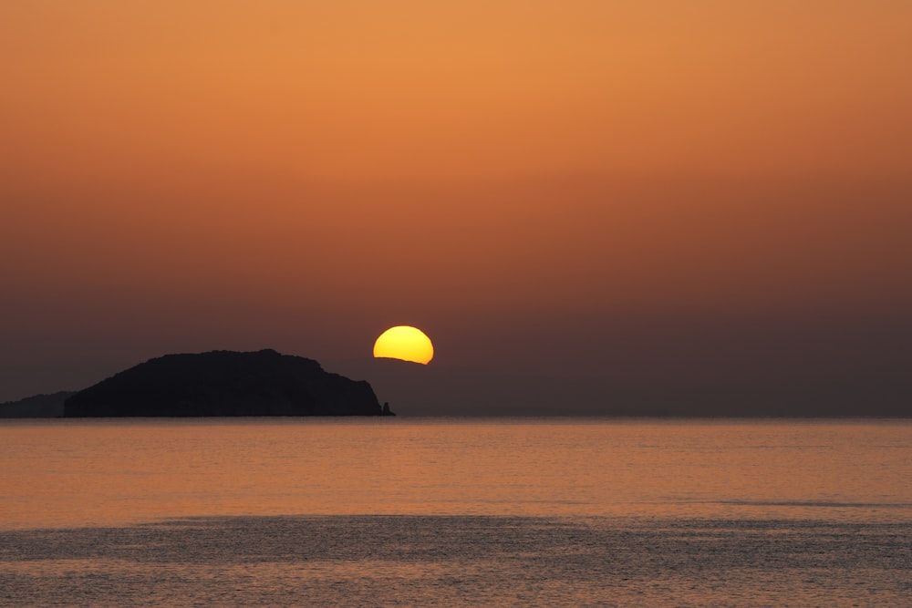 the sun is setting over a small island in the middle of the ocean