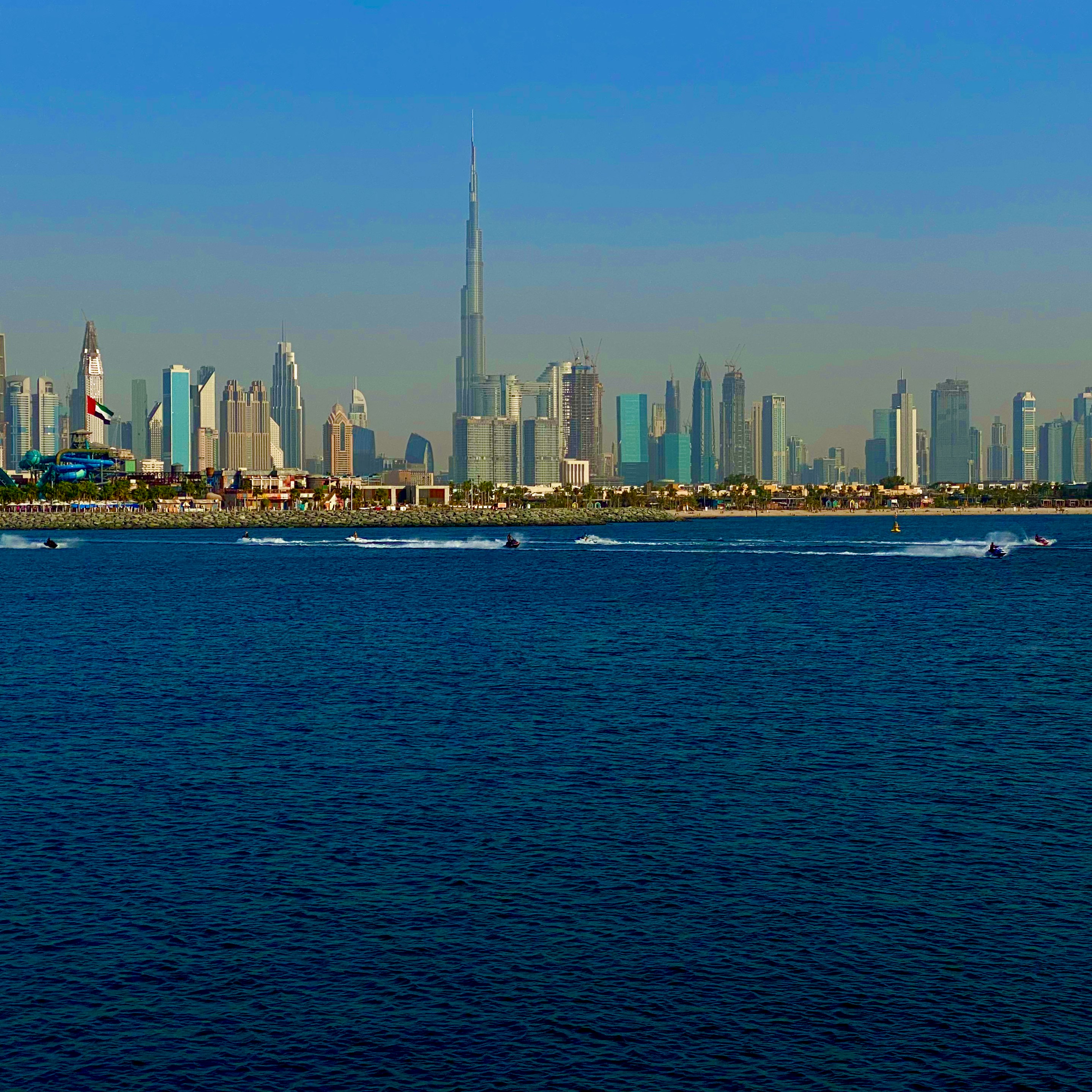 Jetski rider speeding across turquoise Dubai waters with Burj Al Arab in background