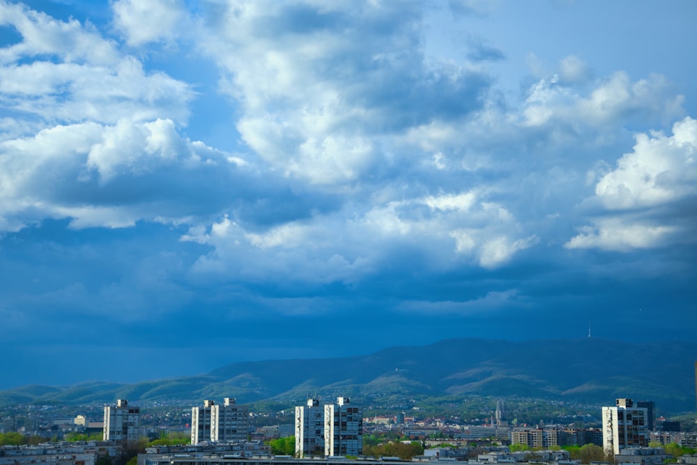 a cloudy sky over a city with mountains in the background