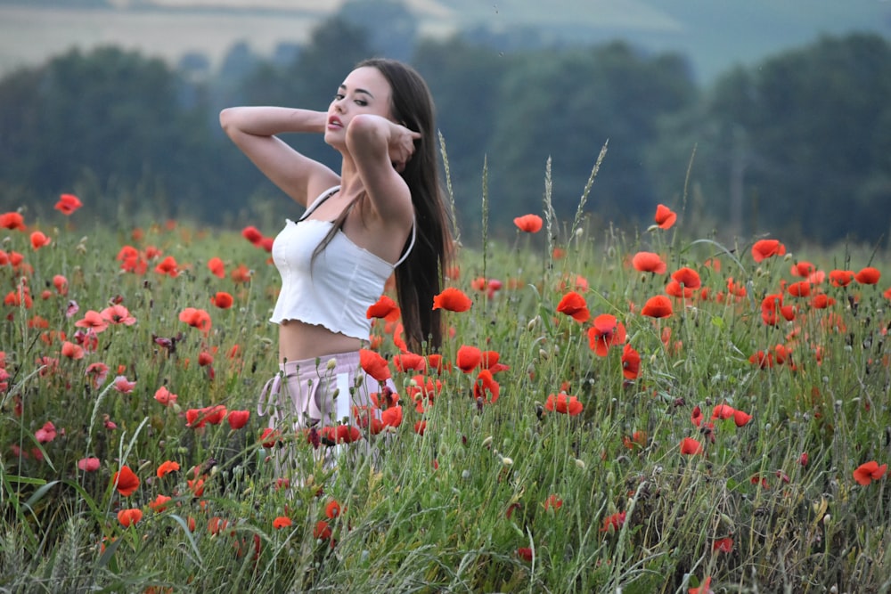 a woman standing in a field of red flowers