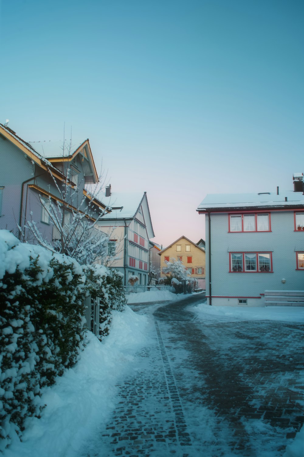 a snow covered street next to a row of houses