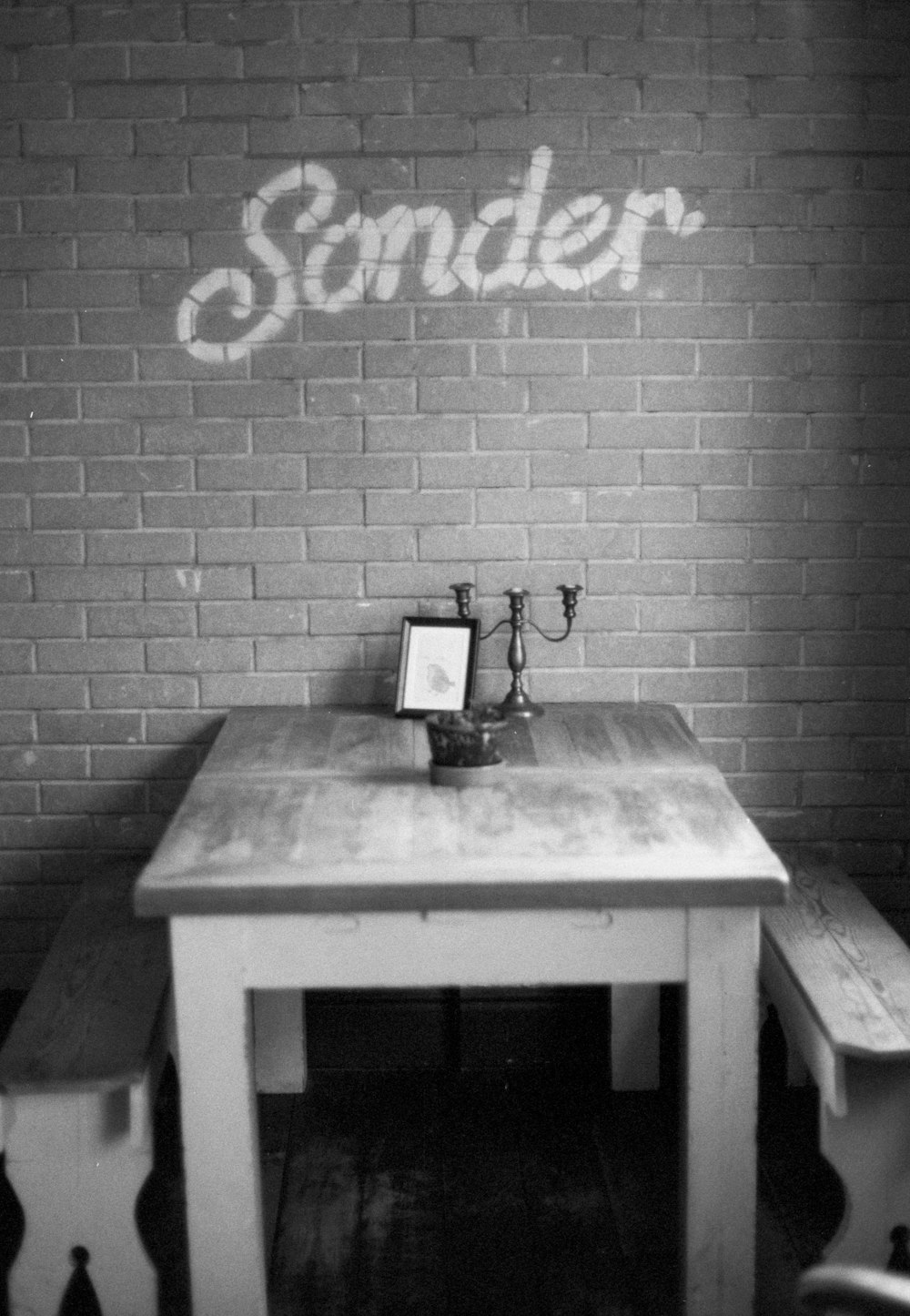 a wooden table with two benches in front of a brick wall