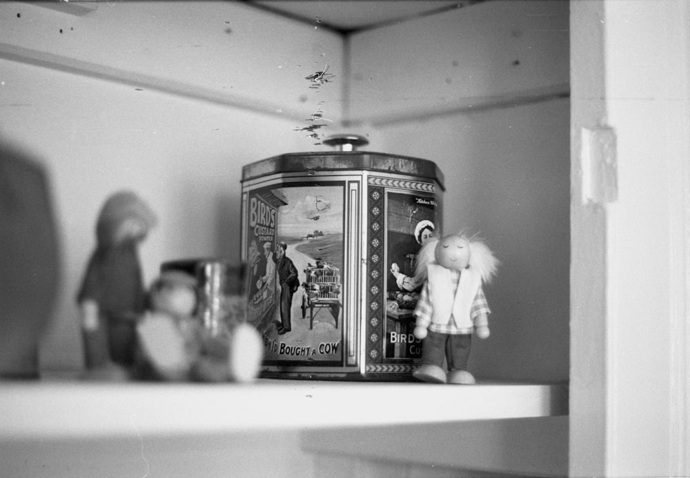 a black and white photo of a shelf with dolls on it